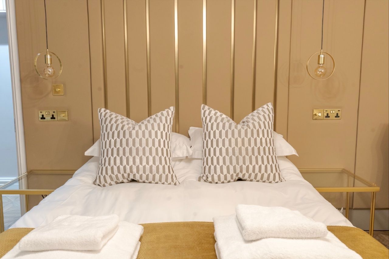 King-size bed with gold panelled headboard and white linen