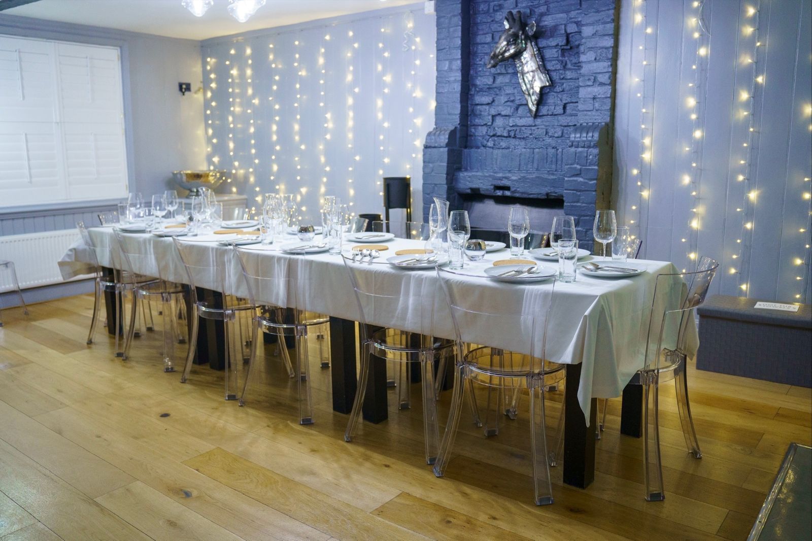 Long dining table laid for a celebration dinner under fairy lights