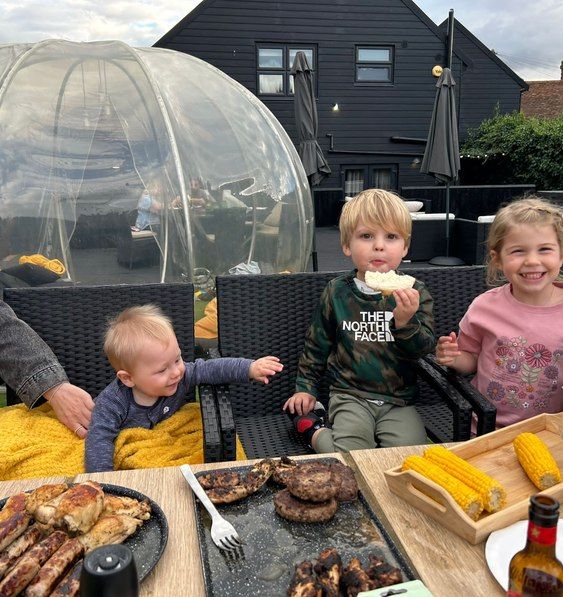 Children enjoying a barbecue in the garden by the igloo