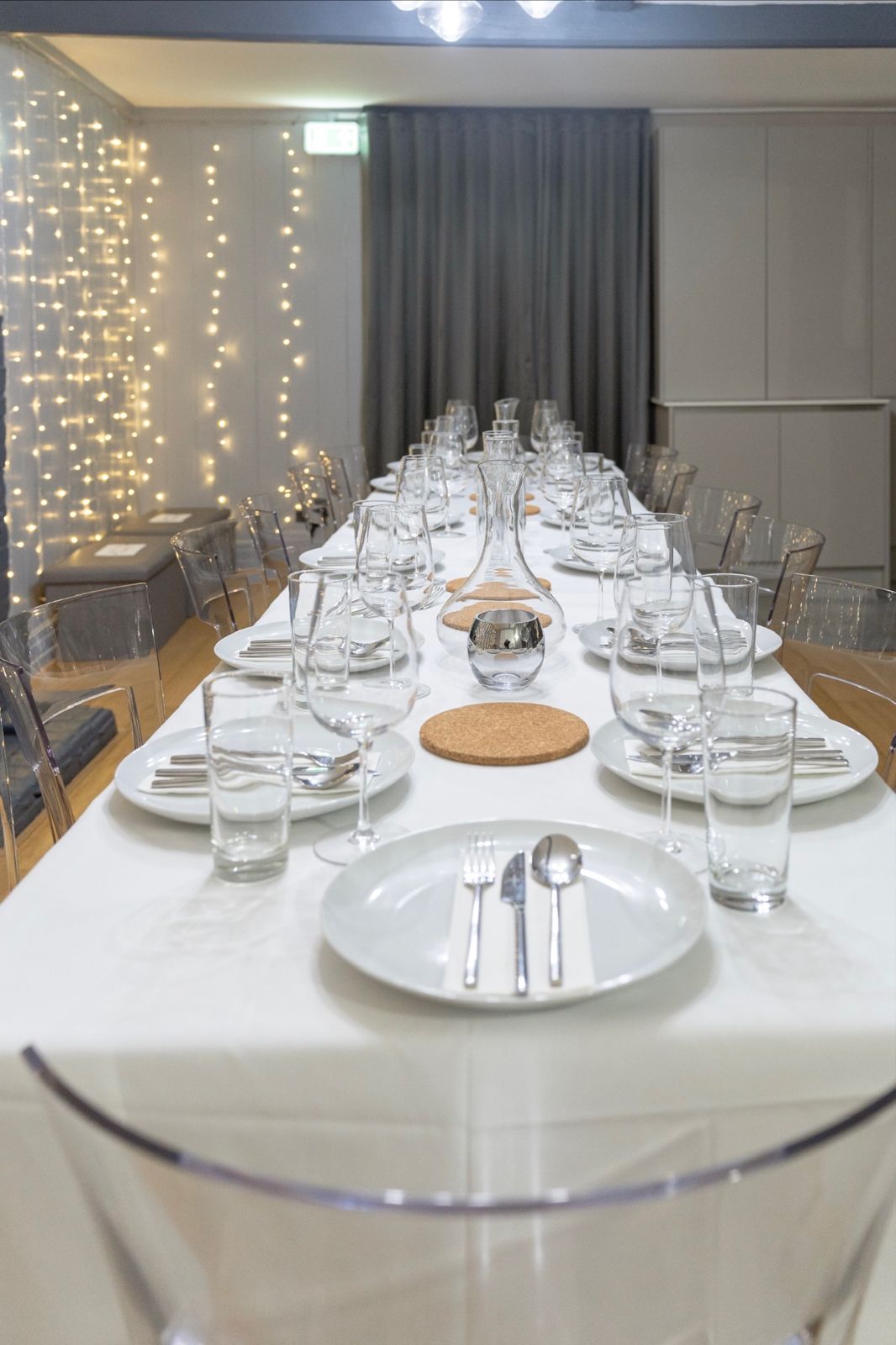 Long table laid with glassware under fairy lights