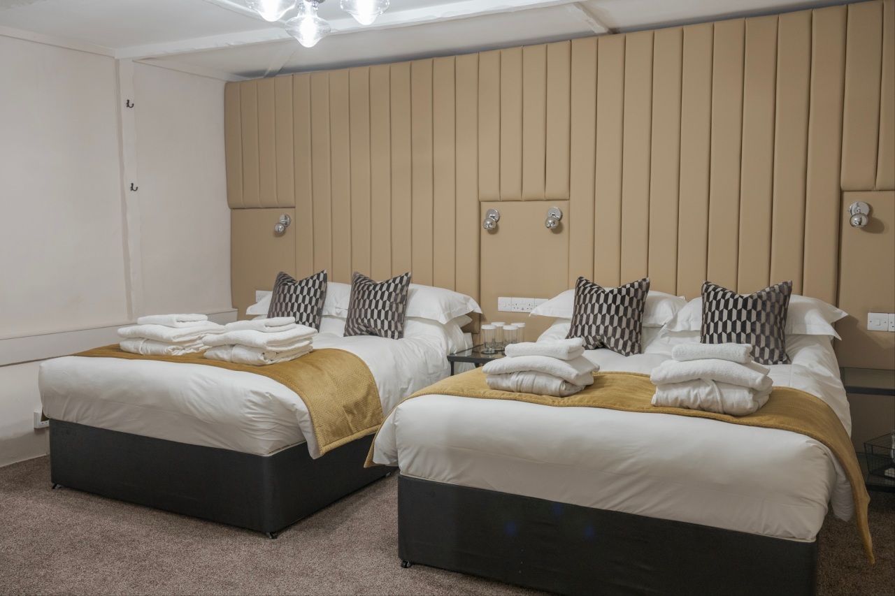 Family room with two double beds, white linen and gold throws